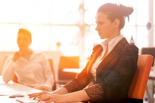 IMAGO Creative, Jahreszeit Frühling, Licht und Sonne RECORD DATE NOT STATED business woman working on desktop computer at modern startup office, people group in background with sunrise or sunset and sun flare in background