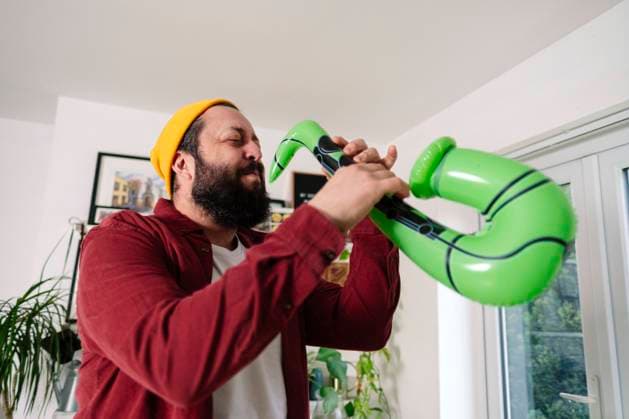 Happy man playing with inflatable saxophone at home model released, Symbolfoto property released, ASGF03236