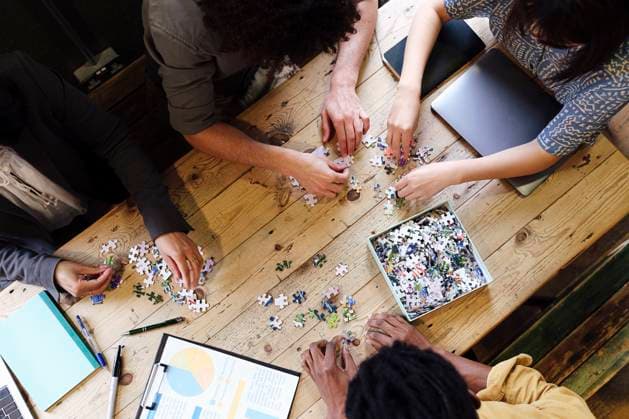 Business colleagues playing jigsaw puzzle game at desk in office model released, Symbolfoto property released, ASGF03377