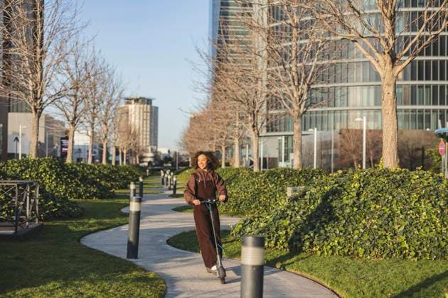IMAGO Creative, Urban Lifestyle Young woman riding push scooter on footpath in city model released, Symbolfoto, JCCMF09405