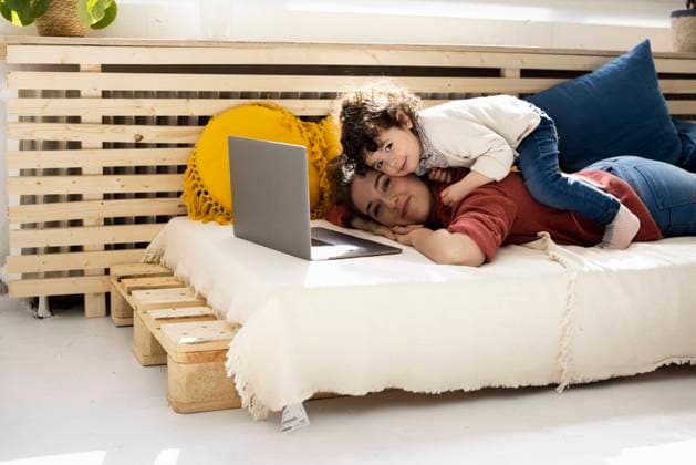 Mother lying on couch working on laptop with daughter sitting on her back model released, Symbolfoto property released, JOSEF09420