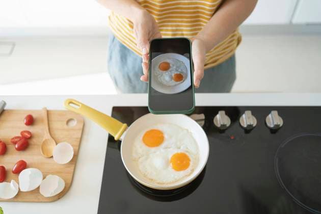 Woman photographing fried eggs with smart phone at home model released, Symbolfoto property released, SVKF01264