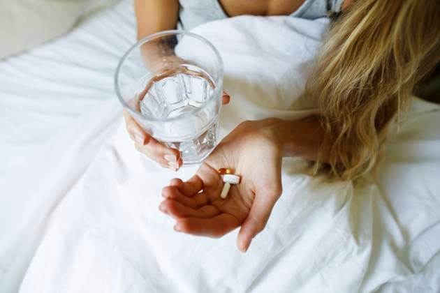 Woman taking pills with glass of water in bed at home model released, Symbolfoto property released, TYF00724