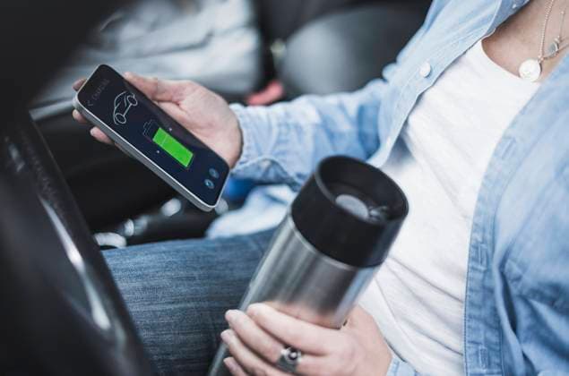 Mature woman with thermos flask using electric car charging app model released, Symbolfoto property released, UUF28043