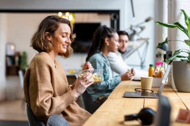 Smiling businesswoman eating salad in lunch break in office model released, Symbolfoto property released, WPEF07038