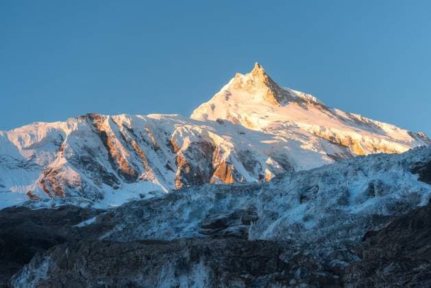 RECORD DATE NOT STATED Beautiful view of snow-covered mountain at colorful sunrise in Nepal. Landscape with snowy peaks of Himalayan mountains, glacier and blue sky in the morning. Amazing Manaslu. Himalayas. Nature