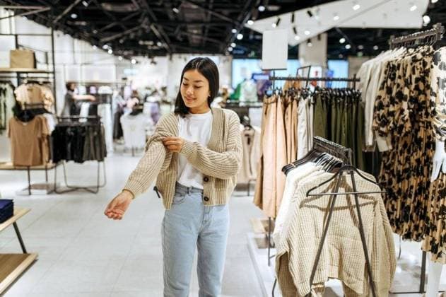 RECORD DATE NOT STATED Young woman trying on cardigan in clothing store. Female person shopping in fashion boutique, shopaholic, shopper looking on garment. Young woman trying on cardigan in clothing store; Jung Frau versuchend am Wolljacke ÊIn Bekleidung Ladengeschaeft weiblich person Einkaufen ÊIn Mode boutique, shopaholic, shopper Schauen am Kleidungsstück Jung Frau versuchend am Wolljacke ÊIn Bekleidung Ladengeschaeft IST_25042_38947