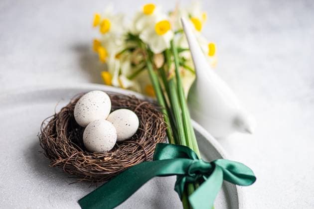 From above easter dinner table set with eggs in the nest and daffodil flowers on concrete background AnnaBogush_ID12998_395386_019 Copyright: xAnnaxBogushx Model Released