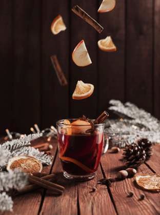 Christmas cup of Mulled Wine on table, levitating cinnamon stick, orange, apple Christmas glass cup or mug with Mulled Wine on wooden table and background with levitating cinnamon stick, dried or sublimated orange, apple slices, present gift boxes, garlands, decoration lights Copyright: xZoonar.com OlenaxIvanovax 17887943