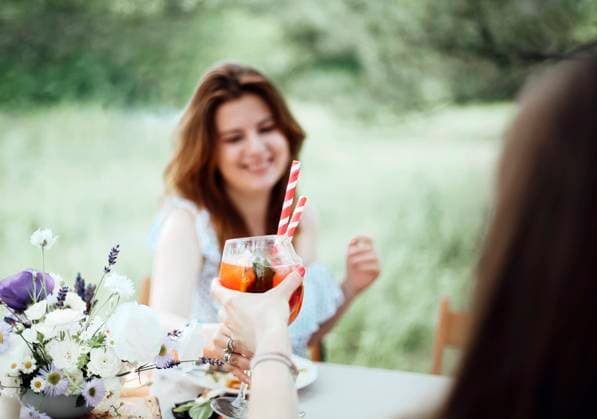 Cheerful woman with cocktail during banquet Happy young female with alcohol cocktail smiling and proposing toast while sitting at table during banquet in garden Copyright: xZoonar.com DashaxPetrenkox 16943769 ,model released, Symbolfoto ,property released
