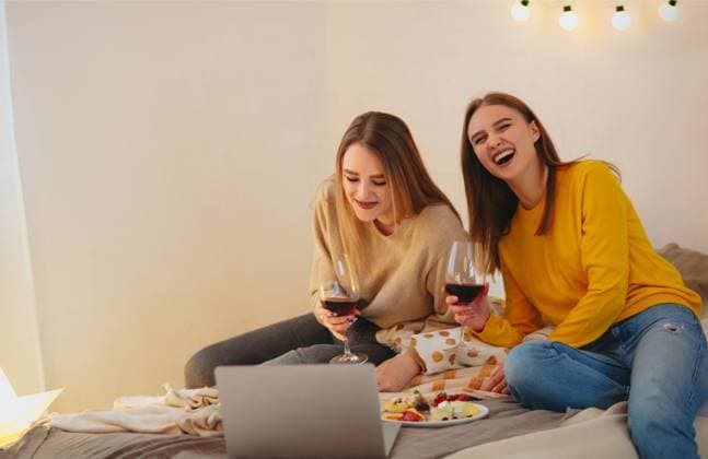 Two cute happy funny women having home cinema evening watching comedy on laptop sitting on bed Two cute happy funny women friends having fun together, arranging home cinema evening, watching comedy on laptop, laughing out loudly, sitting on bed with cheese plate and glasses of red wine Copyright: xZoonar.com DashaxPetrenkox 17469930 ,model released, Symbolfoto ,property released