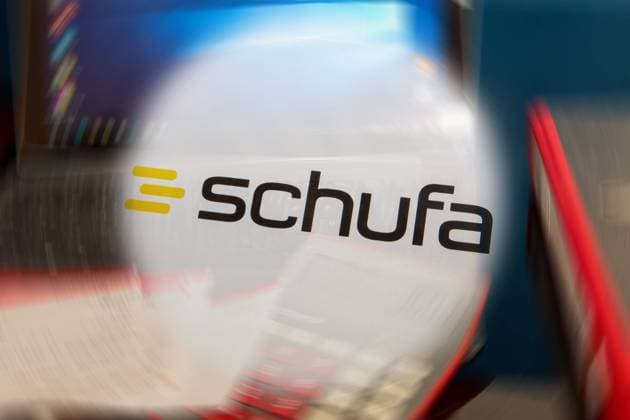 Symbolbild Schufa(Auskunft): Schufa-Logo vor einem Schreibtisch mit Tablet, Taschenrechner und Kontoauszügen *** Symbol image Schufa information Schufa logo in front of a desk with tablet, calculator and bank statements Copyright: xx