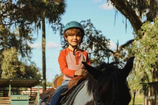 IMAGO Creative, Kinder auf dem Reiterhof RECORD DATE NOT STATED A Caucasian boy wearing helmet and riding horse in greenery field *** einer kaukasisch Junge wearing Helm und reitend Pferd ÊIn Begrünung Feld 10022939 ,model released, Symbolfoto