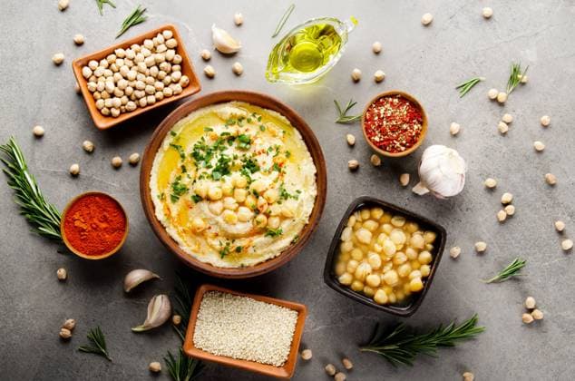 IMAGO Creative, Food, Hummus Hummus topped with chickpeas, olive oil and green coriander leaves on stone table with different spices aside. Flat lay Hummus topped with chickpeas, olive oil and green coriander leaves on stone table with different spices aside. Flat lay Copyright: xZoonar.com OlenaxMykhaylovax 17833996