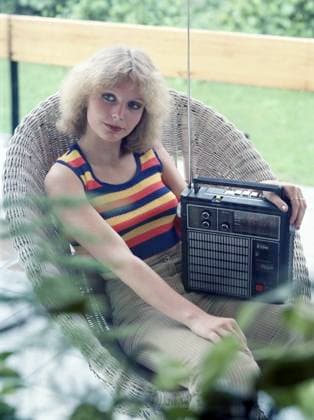 31.08.1979, Berlin, DDR - Junge Frau sitzt in einem Korbsessel und hoert Musik aus einem Kofferradio. (20-30 Jahre, 70er Jahre, Alltag, aussen, Aussenaufnahme, Berlin, DDR, deutsch, Deutsche Demokratische Republik, Deutschland, Europa, europaeisch, Frau, Freizeit, GDR, Geraet, Gesellschaft, HF, historisch, Hochformat, Jahreszeit, Kaukasierin, kaukasisch, Korbsessel, Mensch, Musik hoeren, Ostberlin, Person, pmscartandhistory, R 2310, Radio, Radio hoeren, Radiogeraet, RFT, Rundfunkempfaenger, Rundfunkgeraet, Rundfunktechnik, Siebziger Jahre, sitzen, sitzt, Sommer, Stadt, Stadtleben, Steratrans R2310, Stern Radio, VEB RFT Sternradio Berlin, Ware, Werbeaufnahme, Werbung, Westeuropa, Wirtschaft, Zeitdokument, Zeitgeschichte) 790831A233RFT_WERBUN