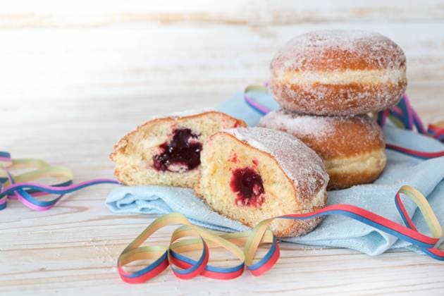 Berliner donuts also called Krapfen filled with jam on a napkin with party streamers, sweet pastry for carnival and New Year, light wooden background, copy space, selected focus Berliner donuts also called Krapfen filled with jam on a napkin with party streamers, sweet pastry for carnival and New Year, light wooden background, copy space, selected focus, very narrow depth of field Copyright: xZoonar.com MARENxWINTERx 18274476