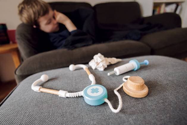 Symbolfoto zum Thema krankes Kind: Ein fuenfjaehriger Junge liegt zu Hause auf einer Couch hinter einem Stethoskop, einer Spritze und einem Taschentuch. Berlin, 14.03.2023 Berlin Deutschland *** Sick child symbol photo A five-year-old boy lies on a couch at home behind a stethoscope, a syringe and a handkerchief Berlin, 14 03 2023 Berlin Germany Copyright: xThomasxTrutschel photothek.dex