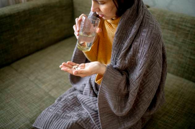 Sick woman wrapped in blanket taking medicine at home model released, Symbolfoto property released, ANAF01017