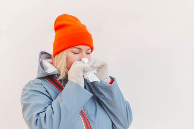 Woman wearing knit hat cleaning nose in front of wall model released, Symbolfoto, IHF01306