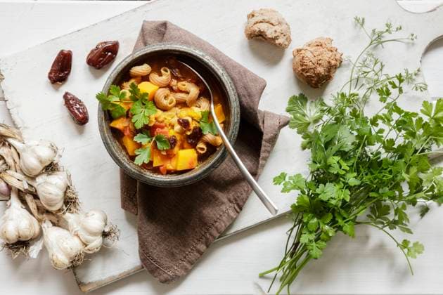 Studio shot of bowl of ready-to-eat North African stew with pumpkin, chickpeas, lentils, dates, cilantro and garlic, EVGF04302