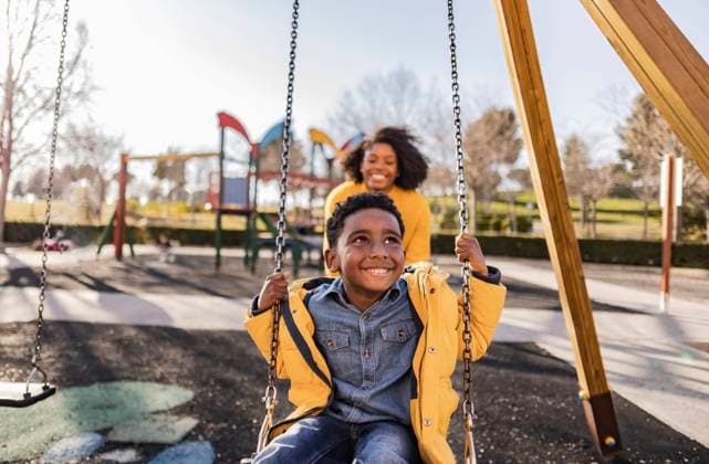 Creative Highlights Symbolbilder Thoughtful son swinging on swing with mother in background model released, Symbolfoto, JCCMF09923