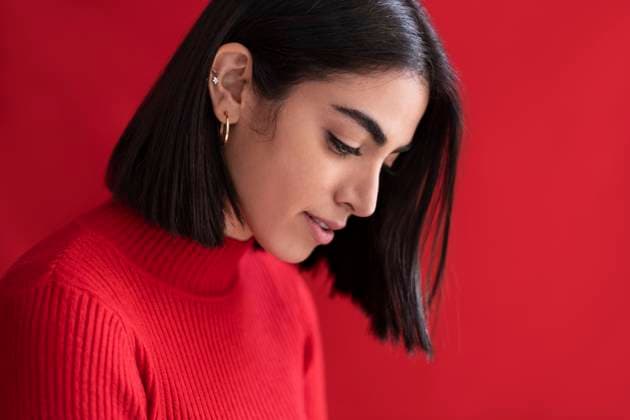 Creative Highlights Symbolbilder Shy young woman looking down against red background model released, Symbolfoto, LMCF00282