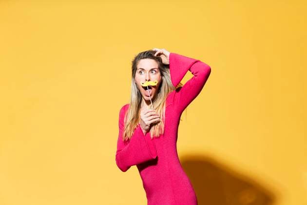 Creative Highlights Symbolbilder Woman with head in hand holding fake mustache against yellow background model released, Symbolfoto, MIKF00172