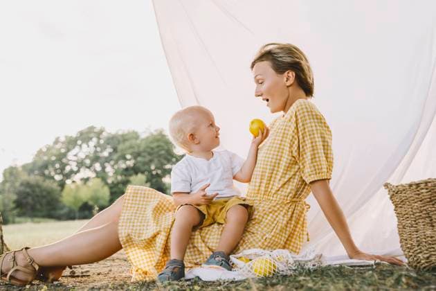 Smiling boy giving fruit to mother sitting in park model released, Symbolfoto, NDEF00399