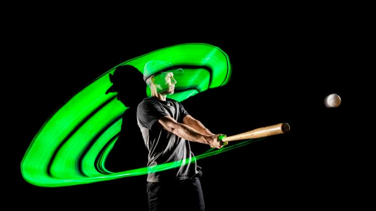 Creative Highlights Symbolbilder Athlete hitting ball with baseball bat against black background model released, Symbolfoto, STSF03697