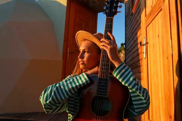 Creative Highlights Symbolbilder Thoughtful woman with guitar at sunset model released, Symbolfoto property released, SYEF00268