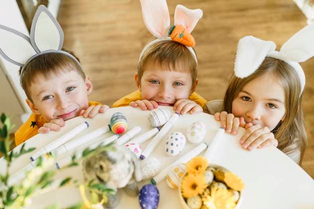 Smiling siblings wearing rabbit ears by table at home model released, Symbolfoto property released, VBUF00268