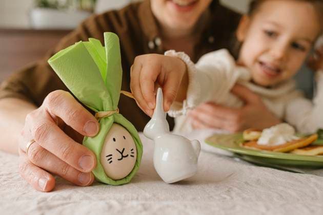 IMAGO Creative, Ostern, Bräuche, Osterbrunch Father and daughter holding bunny and Easter egg at table at home model released, Symbolfoto property released, VIVF00436