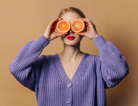 Woman with slices of oranges over eyes against brown background model released, Symbolfoto, VSNF00539