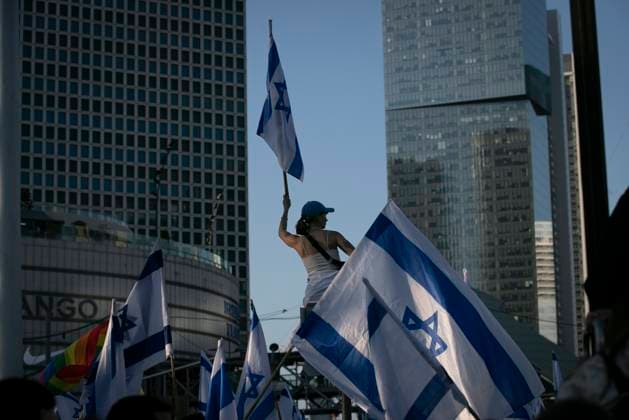 (230327) -- TEL AVIV, March 27, 2023 -- A demonstrator holding an Israeli national flag protests against a judicial overhaul plan in Tel Aviv, Israel, on March 27, 2023. Israeli Prime Minister Benjamin Netanyahu announced on Monday evening that he would suspend the legislation of his contentious plan to overhaul the country s judiciary by about a month to allow dialogue between coalition and opposition lawmakers. He made the remarks in a televised speech, which came after tens of thousands of Israelis rallied outside the parliament on Monday and a general strike started earlier in the day to protest the overhaul. ) ISRAEL-TEL AVIV-JUDICIAL OVERHAUL PLAN-PROTEST ChenxJunqing 