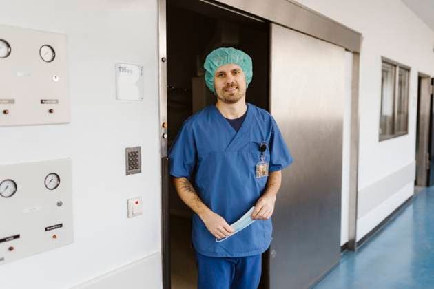 Portrait of smiling physician wearing scrubs standing at doorway in hospital corridor Germany, Berlin, model released, property released Copyright: xMaskotx , MA100120 MA100120