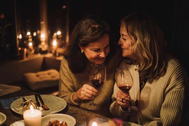 Senior female friends talking and holding wineglasses during candlelight dinner party Sweden, Stockholm, model released, property released Copyright: xMaskotx , MA100173 MA100173