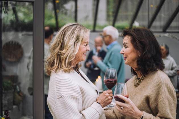 Smiling senior woman with wineglasses talking to female friends at dinner party Sweden, Stockholm, model released, property released Copyright: xMaskotx , MA100191 MA100191