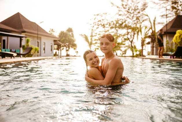 Portrait of brother and sister embracing in swimming pool at resort during sunset Thailand, Ko Lanta, model released, property released Copyright: xMaskotx , MA100512 MA100512