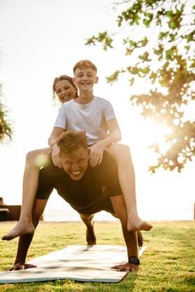 Father carrying children on back while practicing push-ups in park during sunset Thailand, Ko Lanta, model released Copyright: xMaskotx , MA100530 MA100530