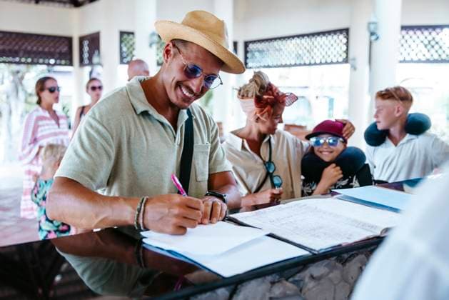 Happy man filling form at resort reception desk during vacation Thailand, Ko Lanta, model released, property released Copyright: xMaskotx , MA100562 MA100562