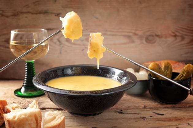 Swiss fondue from melted cheese with bread on long forks, pickles and wine on rustic wooden planks, copy space, selected focus Swiss fondue from melted cheese with bread on long forks, pickles and wine on rustic wooden planks, copy space, selected focus, narrow depth of field Copyright: xZoonar.com MARENxWINTERx 19228507