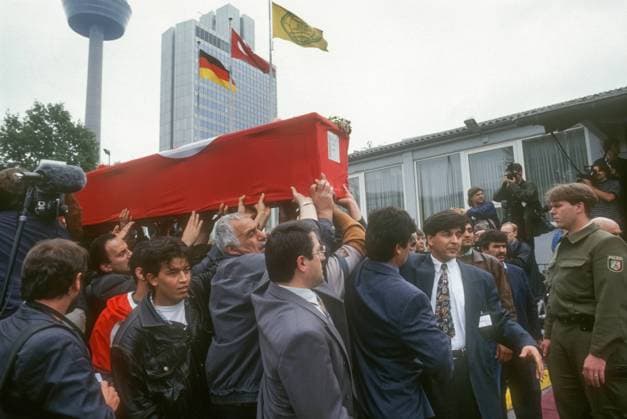 Koeln, Deutschland, DEU - Trauerfeier fuer die Opfer des Brandanschlages von Solingen (29.5.1993) 03.06.1993, Koeln, Deutschland, DEU - Trauerfeier fuer die Opfer des Brandanschlages von Solingen (29.5.1993). Maenner tragen einen Sarg der in einer tuerkischen Fahne eingewickelt ist. Am 29.05.1993 sterben bei einem rassistischen Brandanschlag auf das Haus der tuerkischstaemmigen Familie Genc fuenf Frauen und Maedchen. Der Anschlag war der traurige Hoehepunkt einer deutschlandweiten Welle rassistischer Angriffe auf Fluechtlinge und Migranten. Die Taeter waren vier junge Maenner der oertlichen Neonaziszene zwischen 16 und 23 Jahren. Koeln Nordrhein-Westfalen Deutschland *** Cologne, Germany, DEU Funeral service for the victims of the arson at