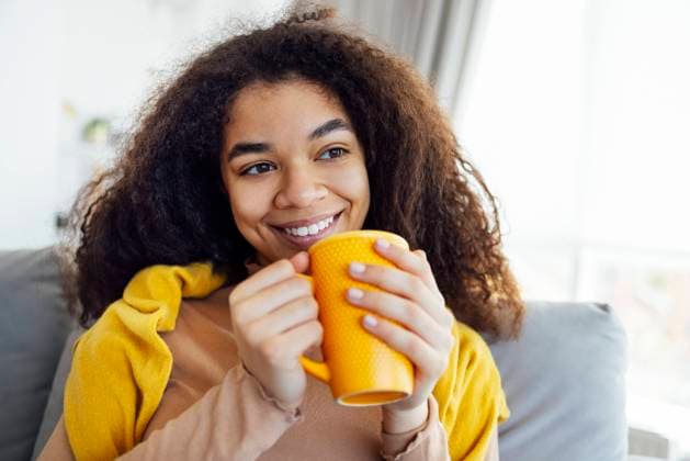 IMAGO Creative: Herbst, Gemütliches Zuhause Cheerful african american girl relaxing on couch with cup of coffee, smiling at camera Cheerful smiling african american girl relaxing on couch with cup of coffee, resting at home, enjoying day off, wearing warm clothes ,model released, Symbolfoto Copyright: xZoonar.com DashaxPetrenkox 19792068 ,model released, Symbolfoto ,property released