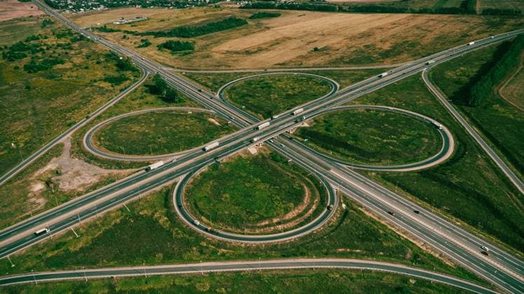 Clover or daisy type of road junction. Aerial view of highway road junction Clover or daisy, simple and cheap type of road junction. Aerial view of beautiful highway road junction in clover shape at summer day. Lorry truck and semi-truck on highway. Car and logistic concept Copyright: xZoonar.com OlgaxSergeevax 19813115