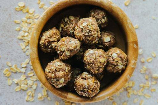 RECORD DATE NOT STATED A top view of oatmeal cookie bites on wooden bowl with spilled oats on the table *** einer Spitze Ansicht des Haferflocken Plätzchen beißt am hölzern Schüssel mit vergossen Hafer am der Tisch 10474583