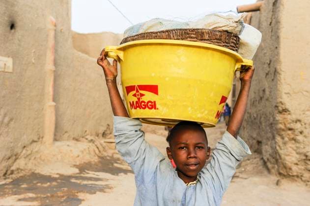 Mali, Maggi ad MALI, Djenne, boy carry plastic bowl with Maggi advertisement, Maggi is a brand of swiss multinational company Nestle *** Junge trägt Plastikschale mit Maggi Werbung, Maggi ist eine Marke des Schweizer Konzern Nestle Djenne Mali