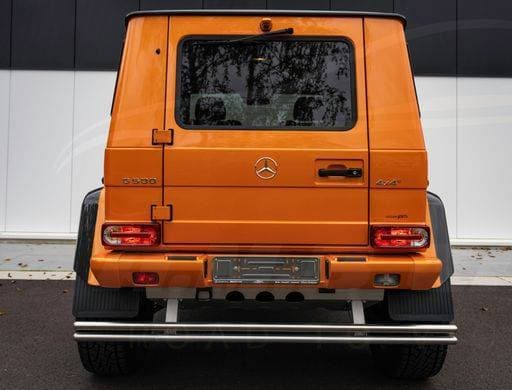 A rear view of a bright orange Mercedes-Benz G-Class SUV parked in a scenic outdoor setting *** einer hintere Ansicht des einer Hell Orangefarbene Mercedes Benz G&P Klasse SUV geparkt ÊIn einer landschaftlich Drauss Einstellung 18764191