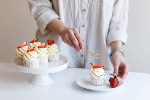 young woman cook tastes cream cupcake with fresh strawberries Lviv, Lviv Oblast, Ukraine R_ORFI230404-1132678-01 ,model released, Symbolfoto