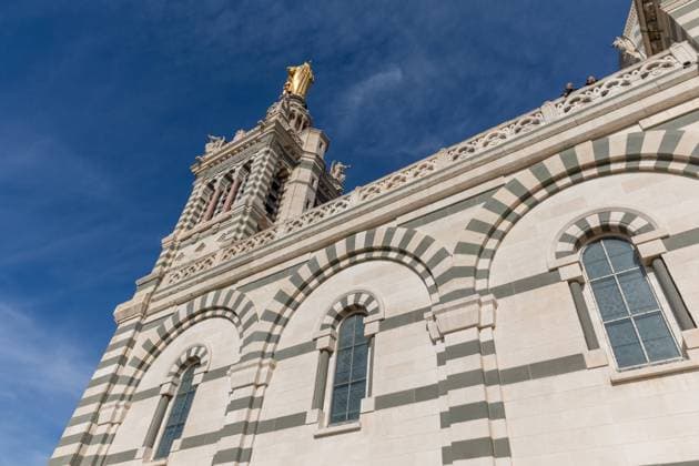 Notre-Dame-de-la-Garde is a stunning Catholic basilica located on a hill overlooking the city of Marseille, in the south of France. The basilica, which is also known as La Bonne Mere (The Good Mother) by the locals, is one of the most iconic landmarks in Marseille and a must-visit destination for anyone visiting the city.Built in the mid-19th century, Notre-Dame-de-la-Garde is an architectural masterpiece, with a stunning Neo-Byzantine design that blends elements of Romanesque and Gothic architecture. The basilica is built on the site of an ancient fort, and its prominent position on the hill overlooking the city makes it visible from almost every corner of Marseille. *** Notre Dame de la Garde is a stunning Catholic basilica located on