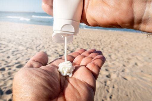 IMAGO Creative, Jahreszeit Sommer, Sonnenschutz RECORD DATE NOT STATED A man applying sunscreen cream to his hands on the beach *** einer Mann applying sunscreen Creme an seinem Hände am der Strand 2209737